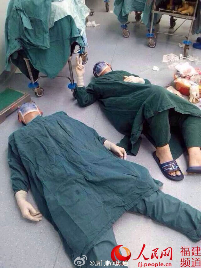 На фотографии: После операций на протяжении 32 часов Чэн Цзин и Чэнь Сун лежат на полу рядом с операционным столом.