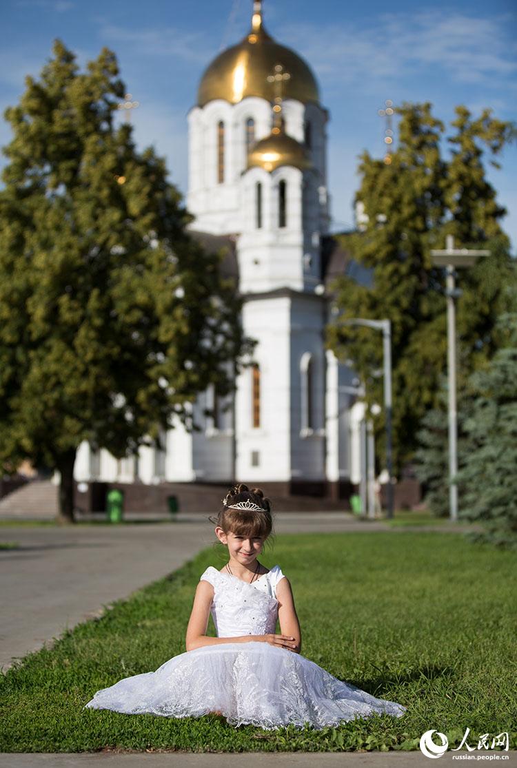 Девушка фотографируется на фоне церкови Георгия Победоносца.
