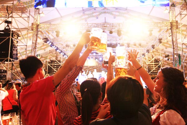 На фото: Гости поднимают стаканы, чтобы отметить торжественное открытие прошлогоднего пивного фестиваля в Олимпийском парке Пекина (Источник – газета China Daily).