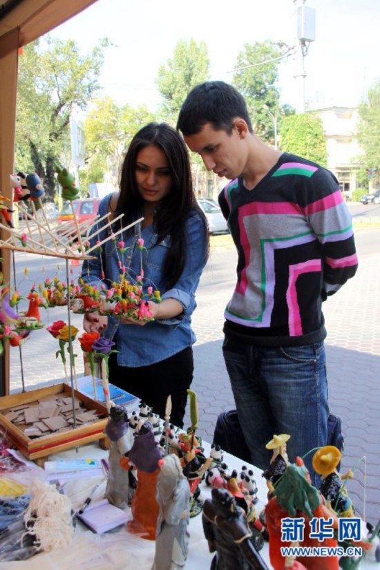 Молодая пара в городе Алматы (Казахстан) любуется глиняными изделиями китайских ремесленников (17 сентября 2013 года).