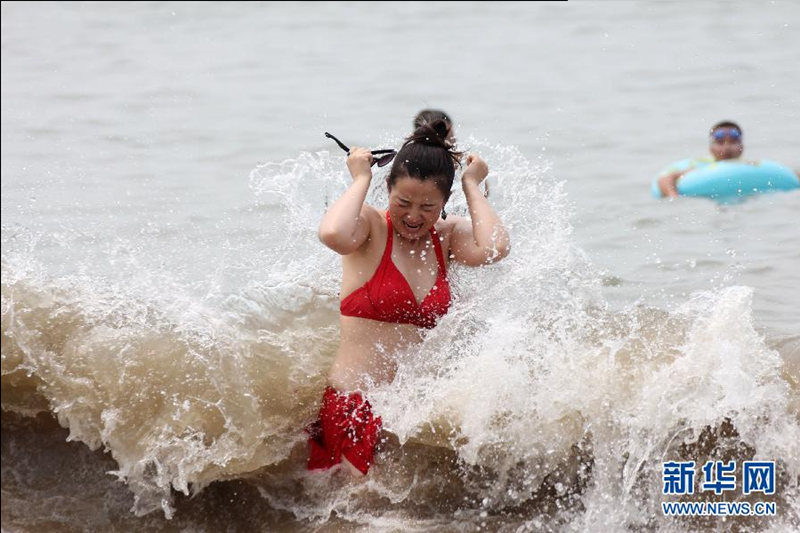 13 июля, жители города Циндао играют на морском пляже.