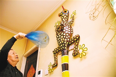 На фото: Чжан Тяньвэй обмахивает веером воздушного змея в форме «геккона»,  и он начинает карабкаться вверх по гладкой стене, мотая головой и виляя хвостом. 