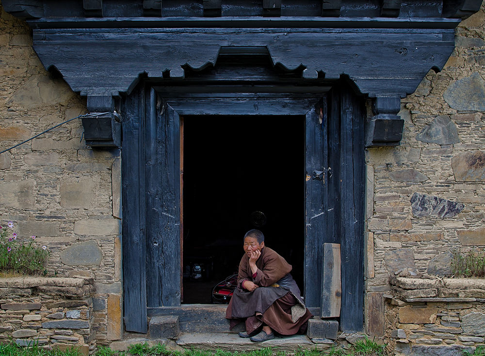 Китай, провинция Сычуань, сентябрь 2014 года.Женщина около своего дома - традиционного жилища в китайском Тибете.