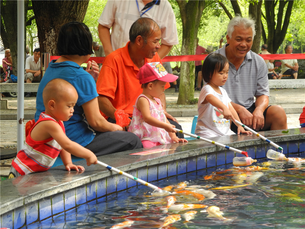 Август 2012 г. Гуйлинь. Малыши кормят рыбок из бутылочек в городском парке. 