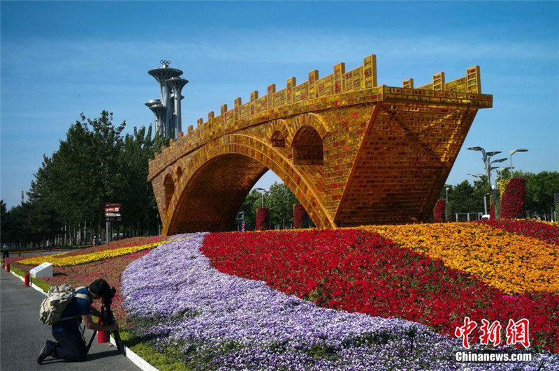 На фото: 7 мая фотолюбитель снимает цветочную клумбу «Золотой мост Великого Шелкового пути» на площадке пекинского Государственного центра собраний.
