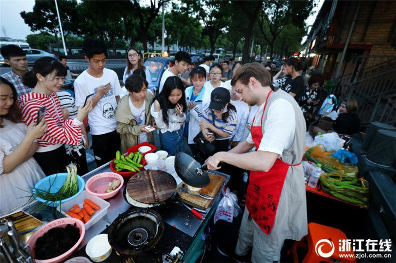 Русский парень готовит блюда китайской кухни на ночном рынке в Ханчжоу