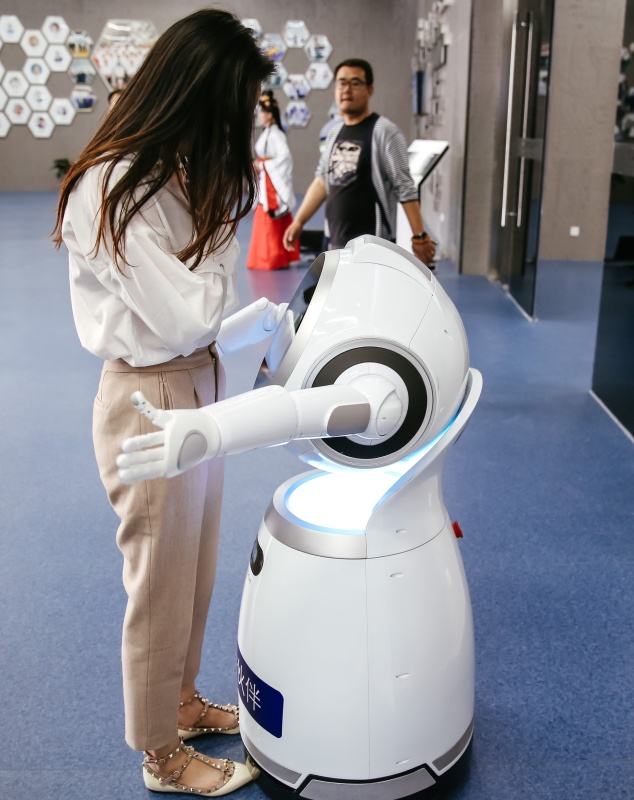 На фото: Интеллектуальный интерактивный робот обнимает посетителя. Он общается с людьми, умеет петь и танцевать.