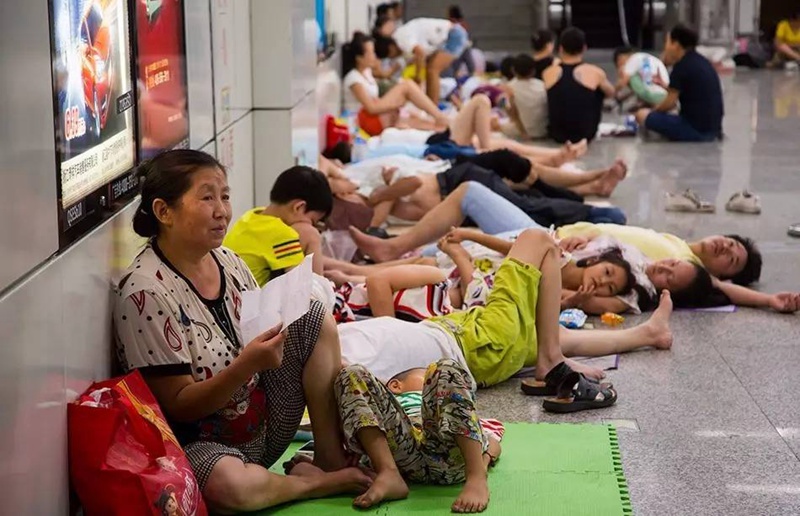 На станции метро в городе Ханчжоу многие жители города сидят под струями холодного воздуха, исходящего из кондиционера. 
