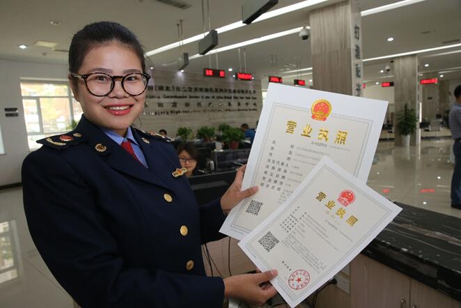 12 мая 2017 г. утром в центре правительственных услуг района Сянъян испытательной зоны свободной торговли провинции Хубэй управленческий персонал по промышленности и торговле показал первую лицензию «9 в 1» на ведение коммерческой деятельности. Источник фото: «Жэньминь шицзюэ»