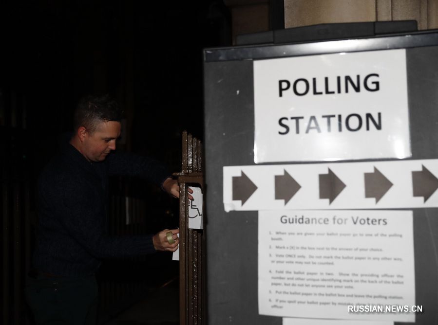 12 декабря, Лондон. Работник открывает дверь участка для голосования /Фото: Синьхуа/