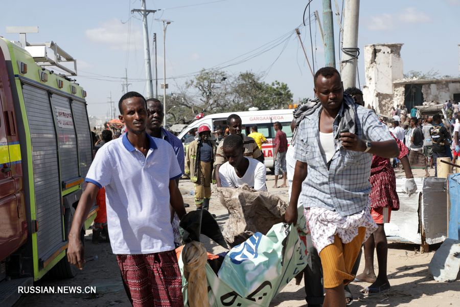 28 декабря на месте взрыва в Могадишо люди переносят раненых. На КПП на окраине Могадишо произошел взрыв заминированного автомобиля, в результате чего 79 человек погибли, еще 149 получили ранения. /Фото: Синьхуа/