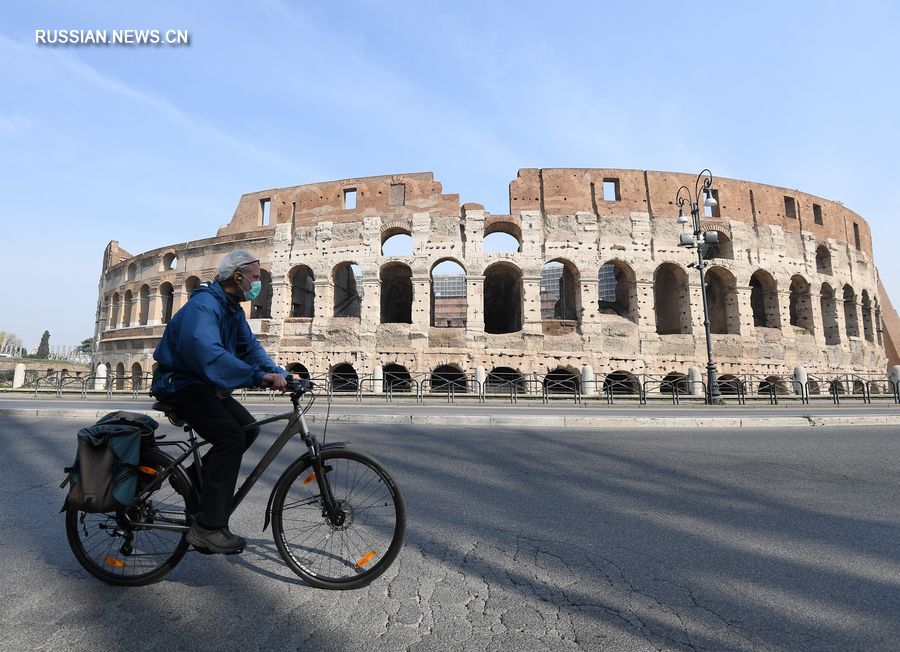 На фотографии, сделанной 22 марта в Риме, изображен мужчина в маске, проезжавший мимо Колизея на велосипеде. /Фото: Синьхуа/