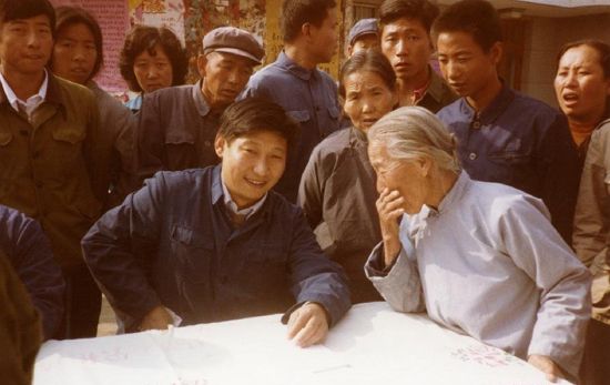 Этот снимок был сделан в 1983 году в уезде Чжэндин провинции Хэбэй, Си Цзиньпин, секретарем уездного парткома, сидел за столом на улице, выслушивая мнения местных жителей.