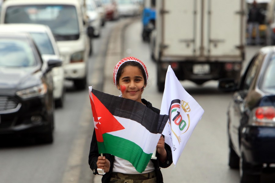 Амман, 11 апреля 2021 года. Девочка держит национальный флаг Иордании и флаг столетия страны по случаю столетия образования королевства. /Фото: Синьхуа/