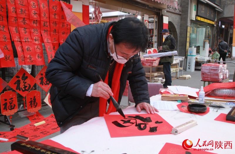 Продавец пишет для покупателя иероглиф «фу» – «счастье». Фото: «Жэньминьван» Цзя Кайлу