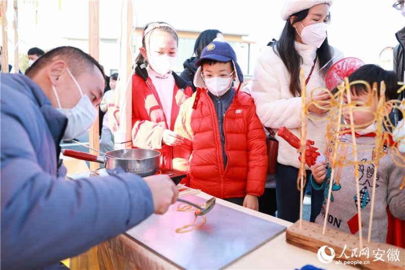 Дети внимательно следят за работой мастера, создающего фигурные леденцы. Фото: «Жэньминьван» Чжан Цзюнь