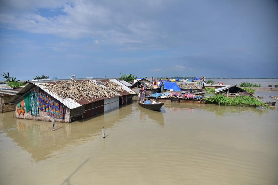 3 июля, штат Ассам, Индия. Жители деревни на лодке возле затопленного дома в пострадавшем от наводнения округе Моригаон. /Фото: Синьхуа/