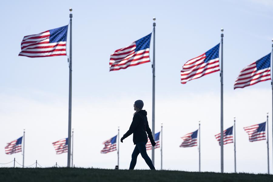 29 марта 2022 года, Вашингтон. Женщина на фоне государственных флагов США. /Фото: Синьхуа/