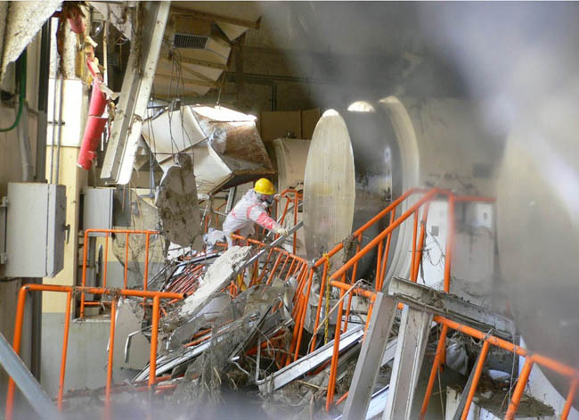 Сотрудники Tokyo Electric Power производят измерения металлических контейнеров для хранения топливных отходов.