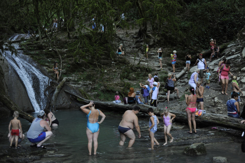 Туристы купаются в водопаде, каждый год сюда приезжает около двух миллионов гостей.