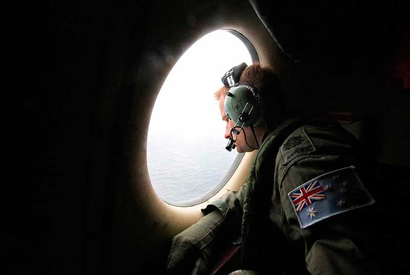 21 марта офицер австралийских ВВС через иллюминатор самолета разыскивает пропавший лайнер Malaysia Airlines MH370 в южной части Индийского океана.